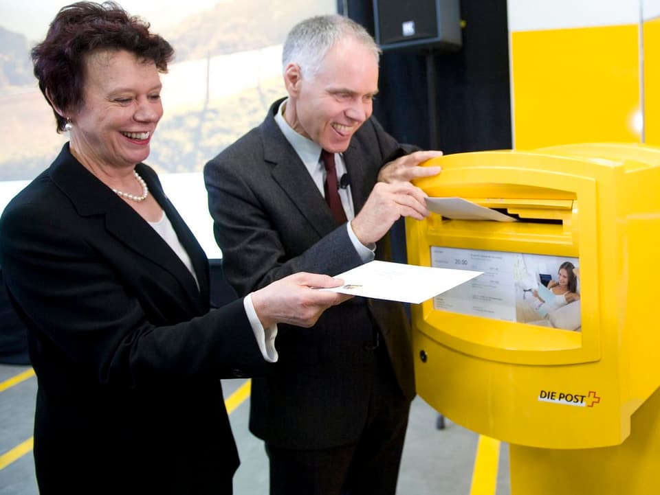 Politiker werfen Brief in einen gelben Briefkasten ein