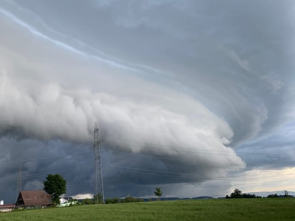 Dunkel Wolke mit bogenförmiger tieferer Wolke über Landschaft.