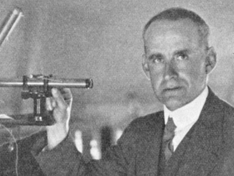 Schwarzweiss-Bild eines Mannes mit einem astronomischen Instrument in der Hand