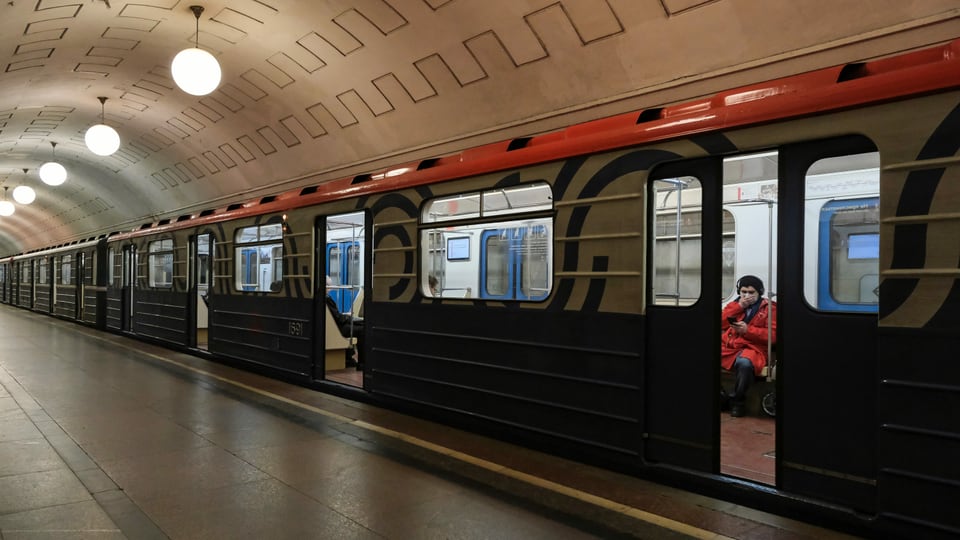 U-Bahn in einer Station, eine Person sitzzt drin, hält die Hand an den Mundschutz