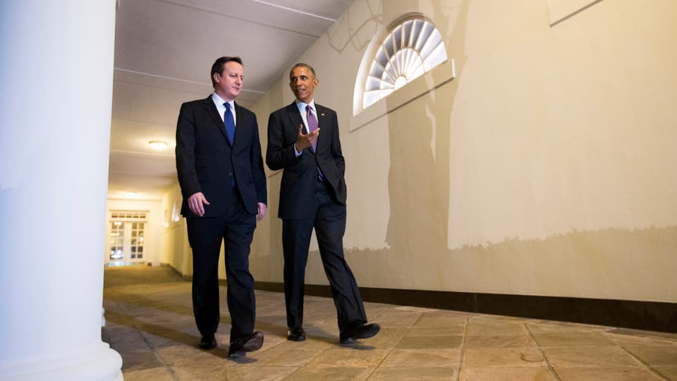 Obama und Cameron schlendern durch einen Gang.