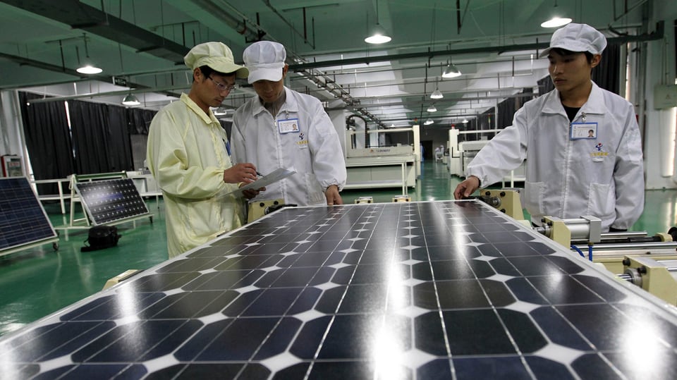 Chinesische Arbeiter vor einem Solarmodul