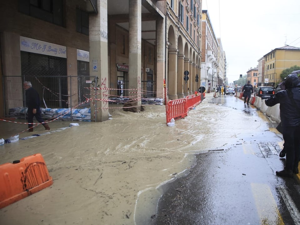 Foto einer Strasse in Bologne. Es hat einen Wasserstrom auf der Strasse, der entlang einer Hausfassade läuft.