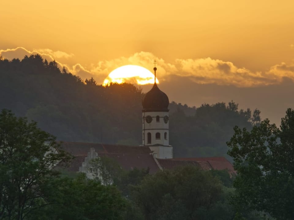 Sun rises over the church tower.