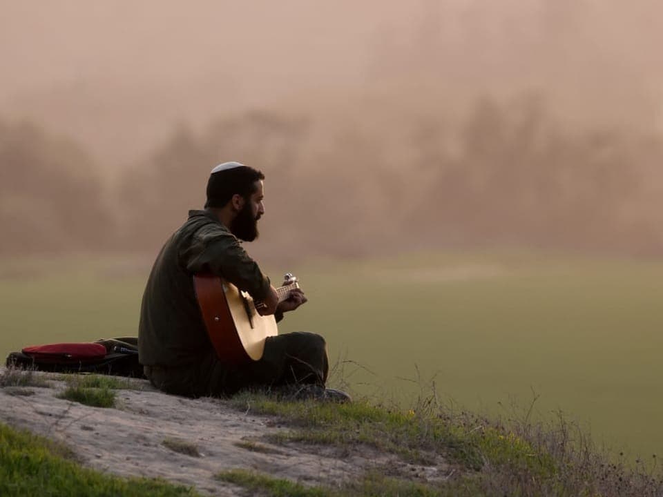 An Israeli soldier plays the guitar on a hill near the border between Israel and Gaza.