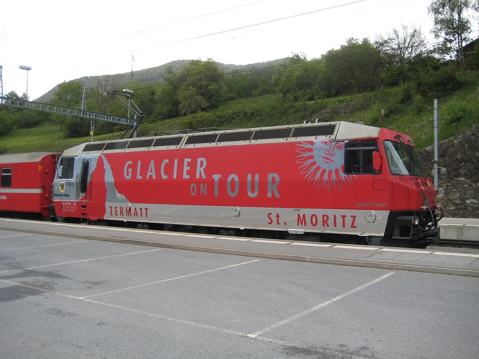 Ein roter Glacier-Express steht an einem Bahnhof.