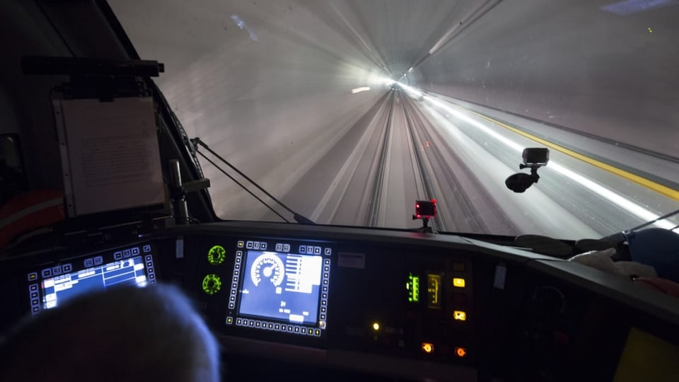 Perspektive des Zugführers im Gotthard-Basistunnel. im Tunnel ist Licht, daneben die Schienen und viel Beton.