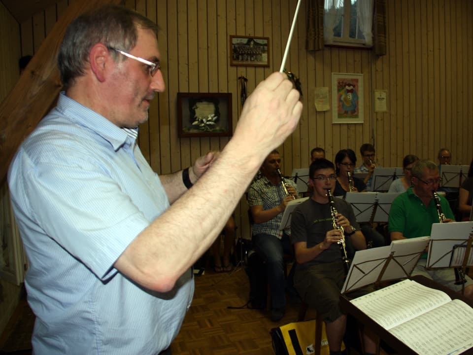 Der Dirigent steht während die Musikantinnen und Musikanten vor ihren Notenblättern sitzen.