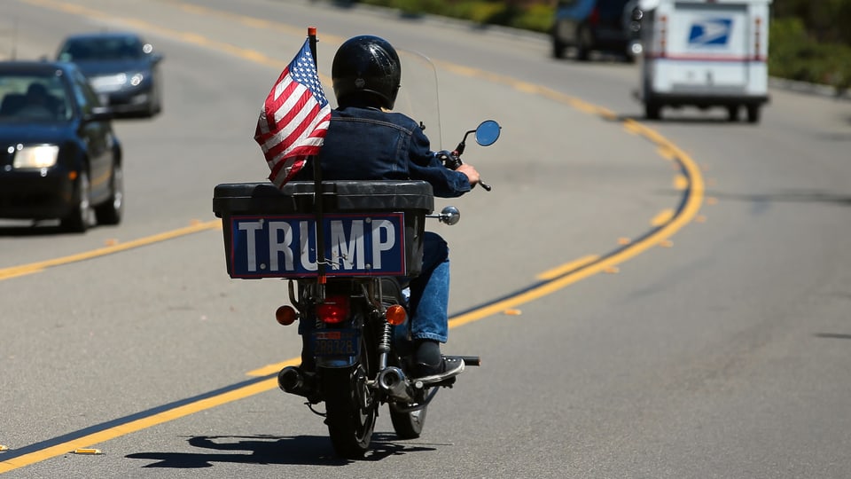 Ein Mann sitzt auf einem Motorrad mit der Aufschrift Trump.