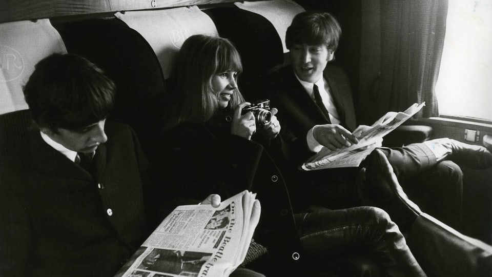 Astrid Kirchherr neben Ringo Starr und John Lennon in einem Zugabteil.