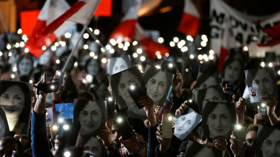 Demonstranten bei Nacht, viele tragen ein Foto der ermordeten Journalistin Daphne Caruana Galizia.