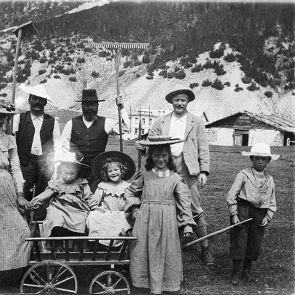 Die Familie des Mitbegründers. Die Männer posieren im Hintergrund mit zwei Harken in der Hand, im Vordergrund sitzen drei Mädchen in langen Kleidern und mit Hüten auf einem Bollerwagen.