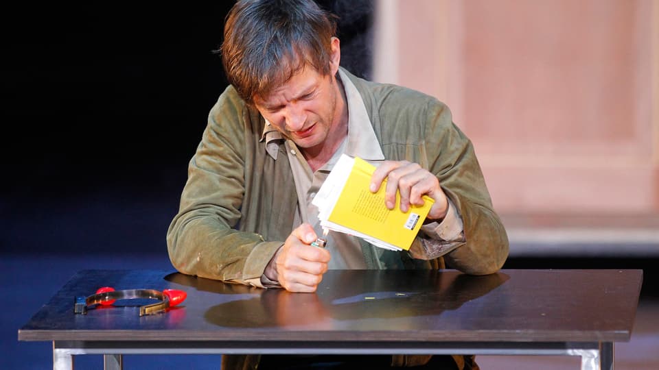 Sebastian Rudolph zündet im Theaterstück «Faust I» ein gelbes Reclamheft mit dem Feuerzeug an.