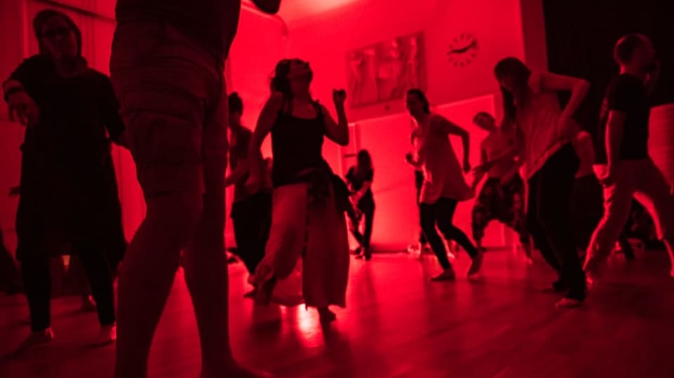Menschen tanzen in einem rot beleuchteten Raum