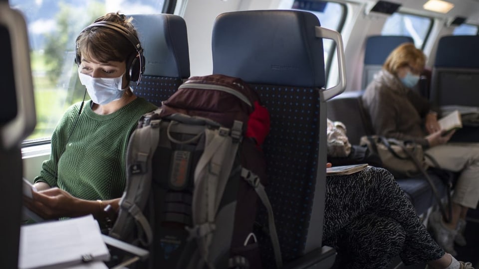 In einem Zugwaggon sitzen zwei Frauen mit Schutzmasken.