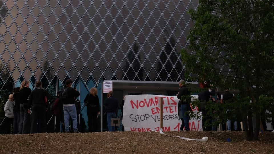 Leute demonstrieren vor dem Novartis-Besucherzentrum.
