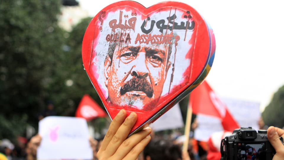 Ein Demonstrant hält ein Herz mit dem Konterfei Belaïds empor.