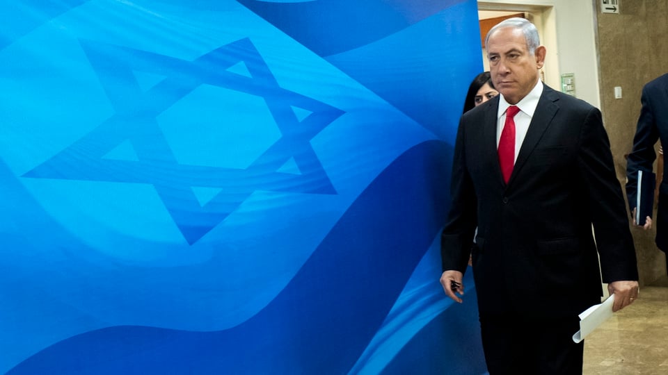 Netanjahu geht vor einer blauen Israel-Flagge vorbei.