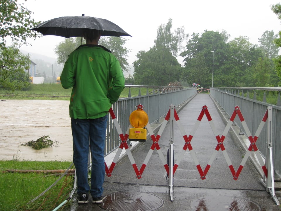 Ein Mann steht vor einer gesperrten Brücke.