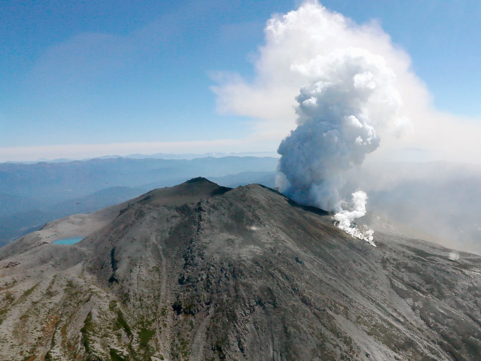 Der rauchende Vulkan Ontake aus der Ferne fotografiert vor blauem Himmel