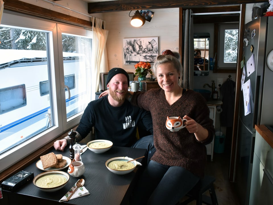 Mann und Frau posieren an einem Tisch mit drei Tellern Suppe. 