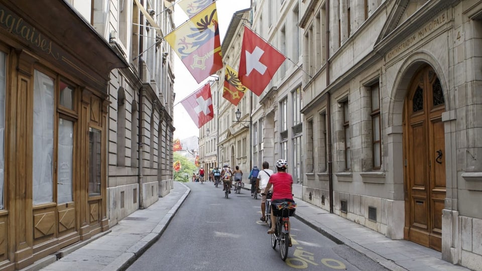 Radfahrer in der beflaggten Genfer Innenstadt.