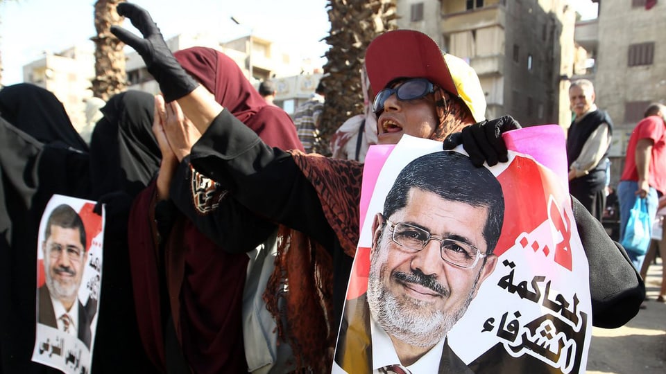 Deonstranten halten ein Poster mit dem Abbild Mursis in der Hand.