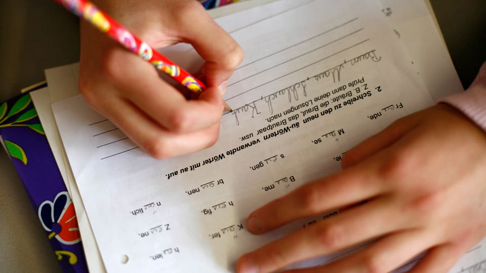 Kind schreibt mit Bleistift auf Blatt Papier