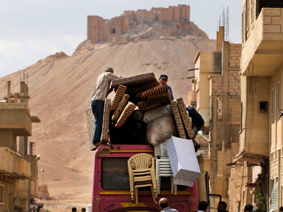 Bewohner Palmyras fliehen aus der Stadt. Im Hintergrund die antike Zitadelle.