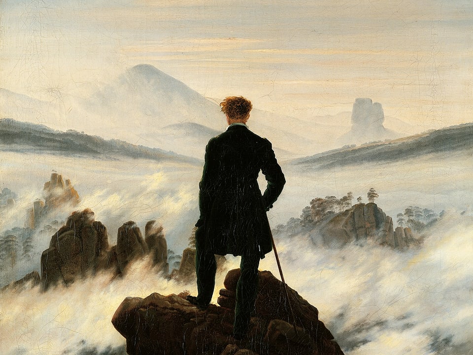 Bild eines Mannes, der auf einem Felsen steht und auf ein Nebelmeer schaut.