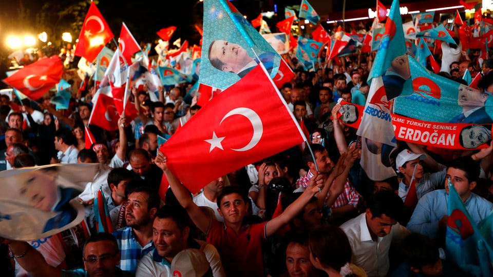Menschen schwenken Türkei- und Erdoganfahnen.