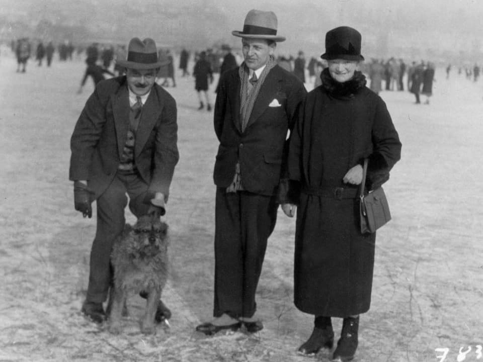 Zwei Männer, eine Frau und ein Hund auf einem gefrorenen See.