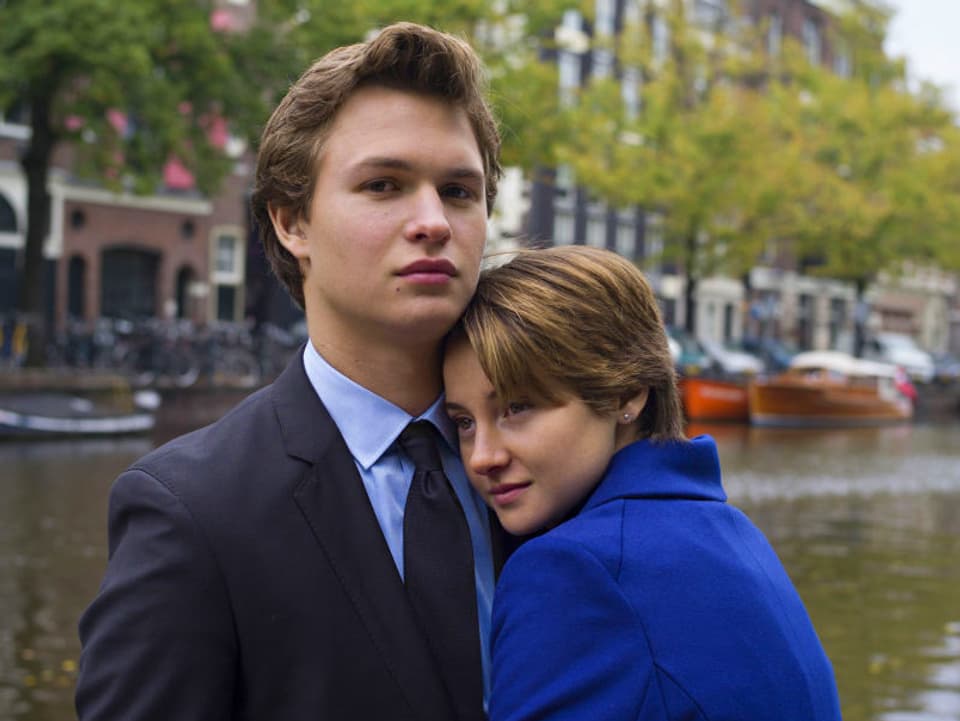 Ein Junge und ein Mädchen schmiegen sich am Rand einer Amsterdamer Gracht aneinander.