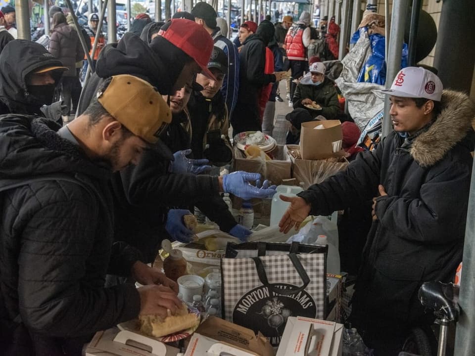 Migrantinnen und Migranten erhalten Essen vor dem Hotel.