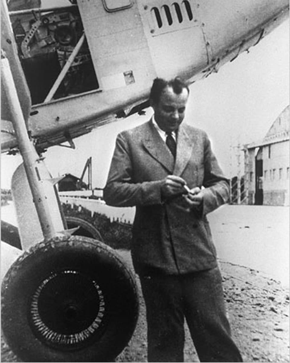 Schwarzweissbild: Saint-Exupéry im Anzug vor einem Flugzeug.