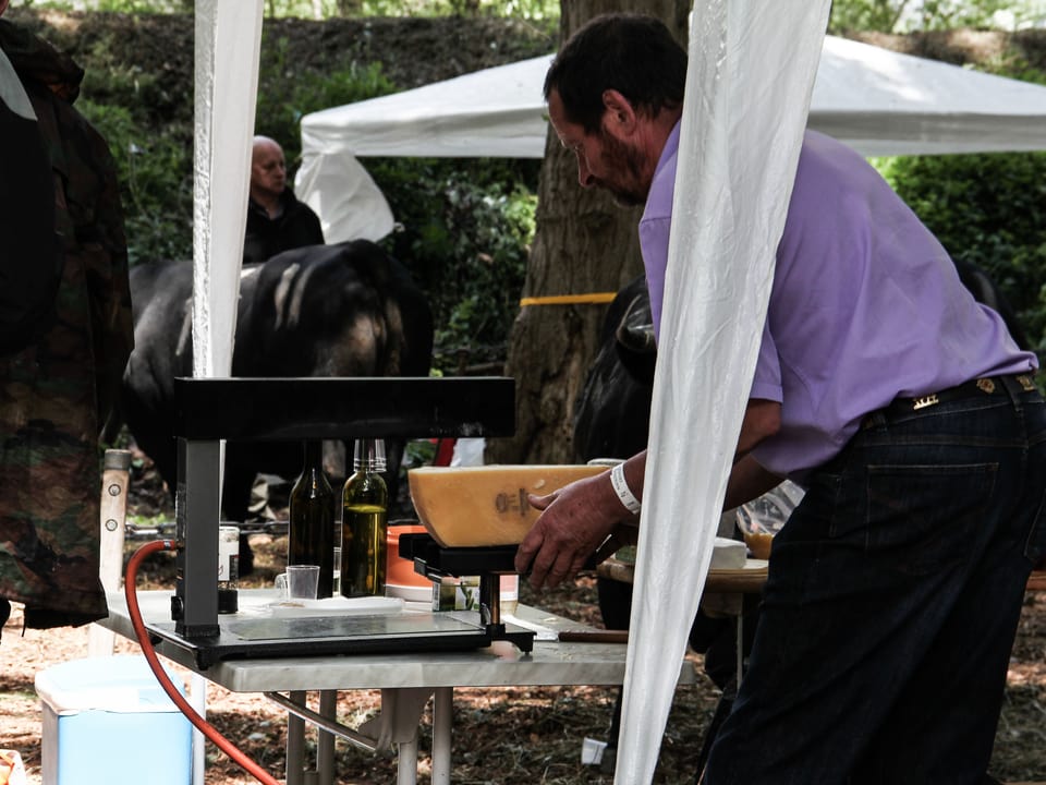 Ein Mann macht Raclette auf einem Ofen.