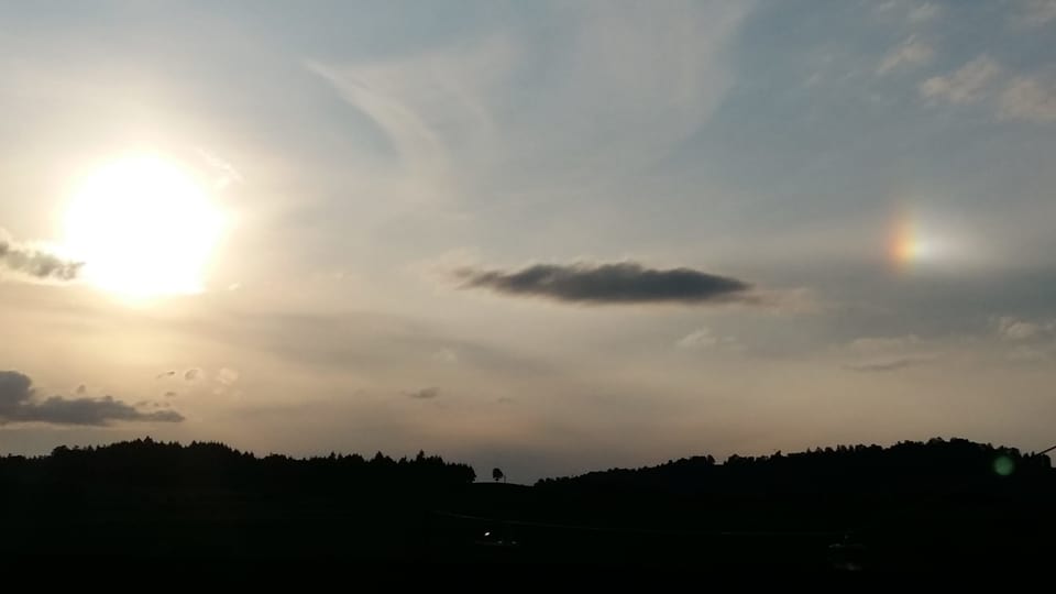 Abendhimmel mit Schleierwolken und der Sonne am linken Rand. Rechts am Rand ist eine weitere helle Stelle erkennbar.