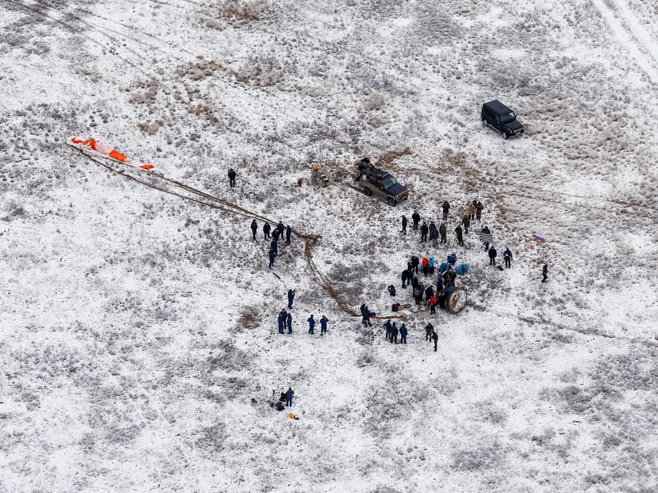 Luftaufnahme des Landeplatzes mit zahreichen Menschen rund um die Kapsel stehend