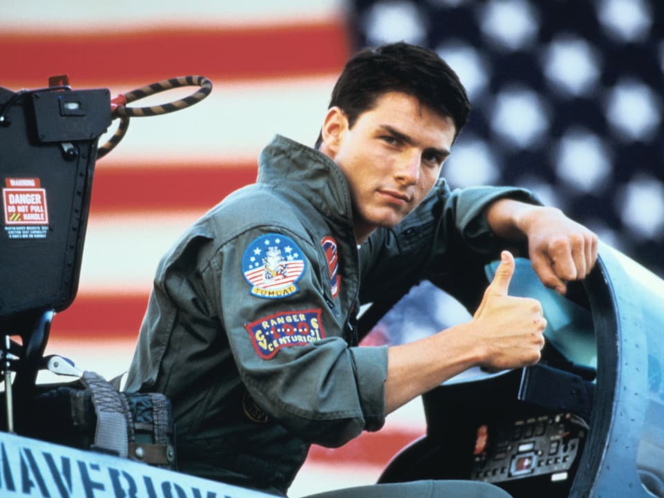 Tom Cruise in Fliegeruniform und hochgestrecktem Daumen im Cockpit eines Kampfjets