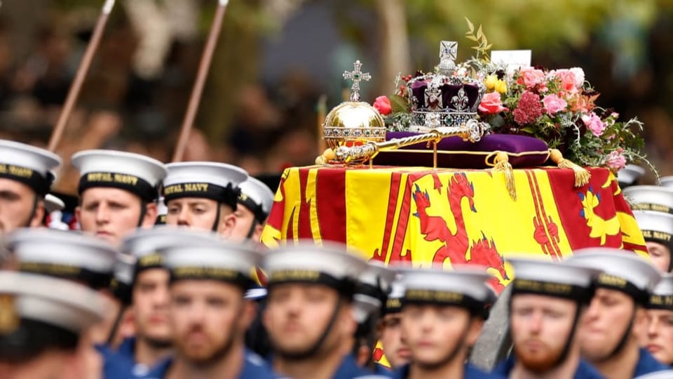 Soldiers pull the Queen's coffin with a crown and letter on it.