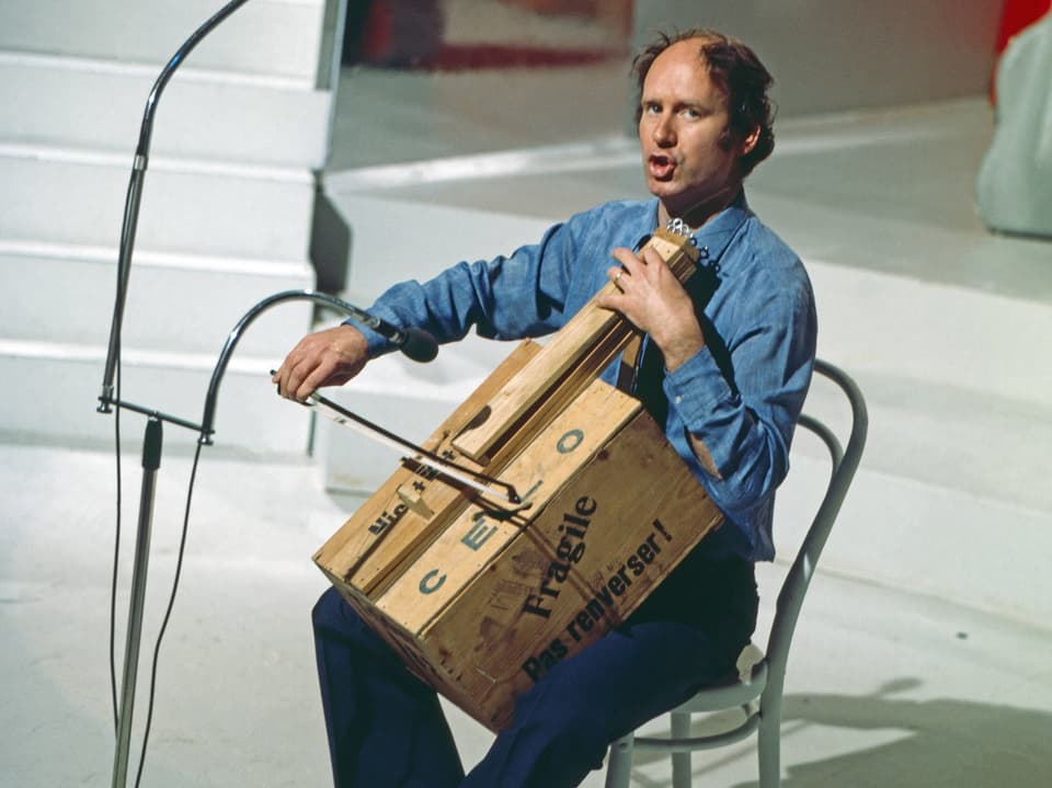 Franz Hohler plays the cello on an instrument made from a wooden box.