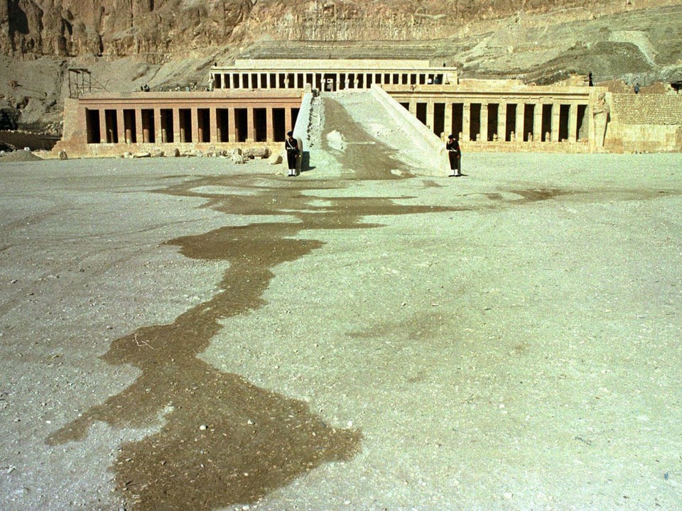 Zu sehen ist die Ausgrabungsstätte von Luxor mit einer Lache Wasser davor.