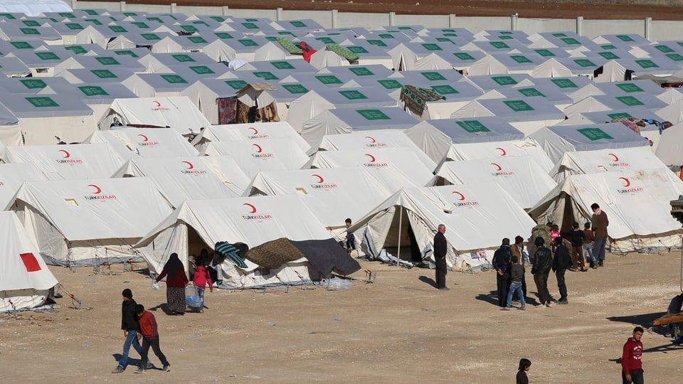 Ein Flüchtlingscamp mit weissen Zelten, die mit dem roten Halbmond gekennzeichnet sind.