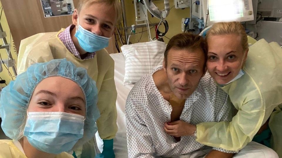 Nawalny sitzt auf einem Krankenbett. Neben ihm seine Familie. 