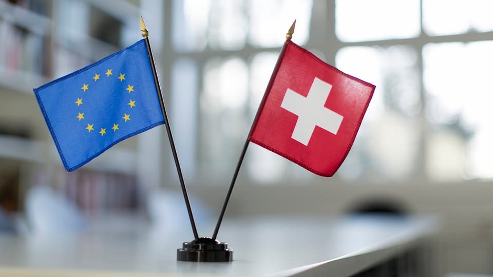 Kleine Fahnen von der EU und der Schweiz auf einem Tisch