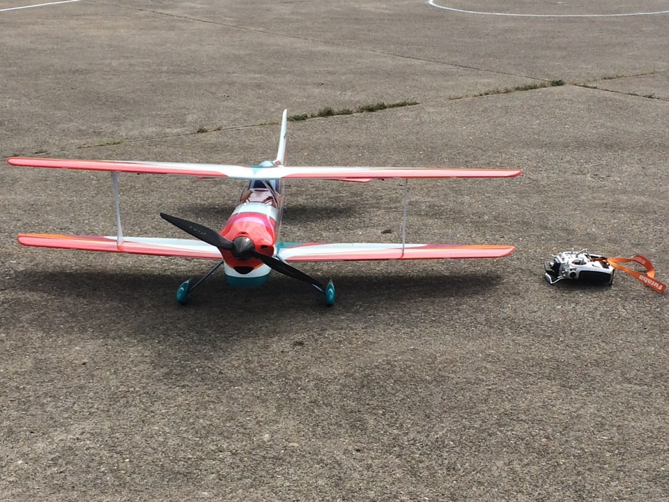Ein Modellflugzeug am Boden, daneben die Fernsteuerung.