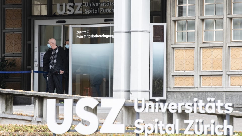 Eingang zum Universitätsspital Zürich, ein Mann mit Maske kommt aus dem Gebäude.