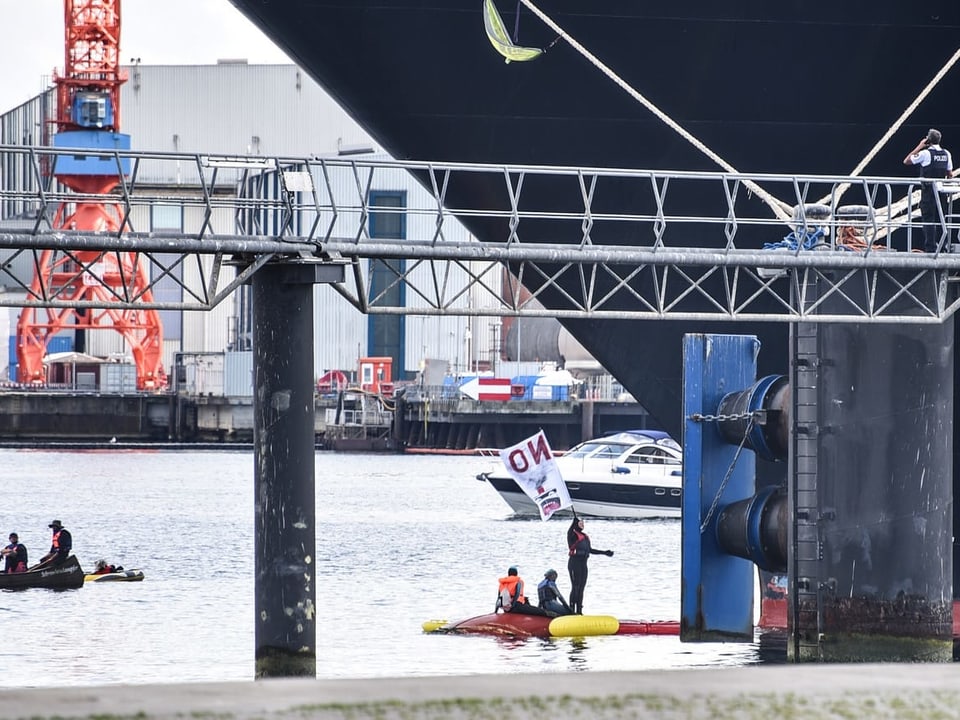 Blick auf den Kieler Hafen und Aktivisten in einem Schlauchboot vor dem Kreuzfahrtschiff