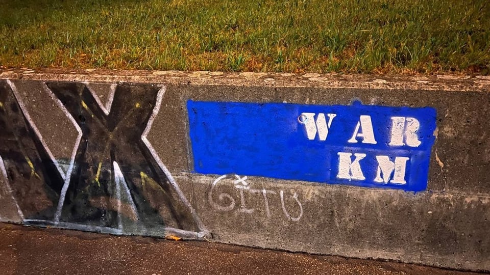 Auf dem Bild ist eine Mauer zu sehen, die bereits mit Graffiti besprüht wurde. Daneben ist ein blaues Rechteck sichtbar.