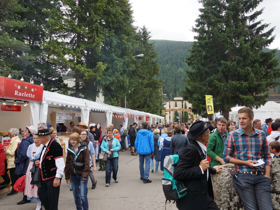 Festivalbesucher - zum Teil in Trachten - flanieren den Essständen entlang.